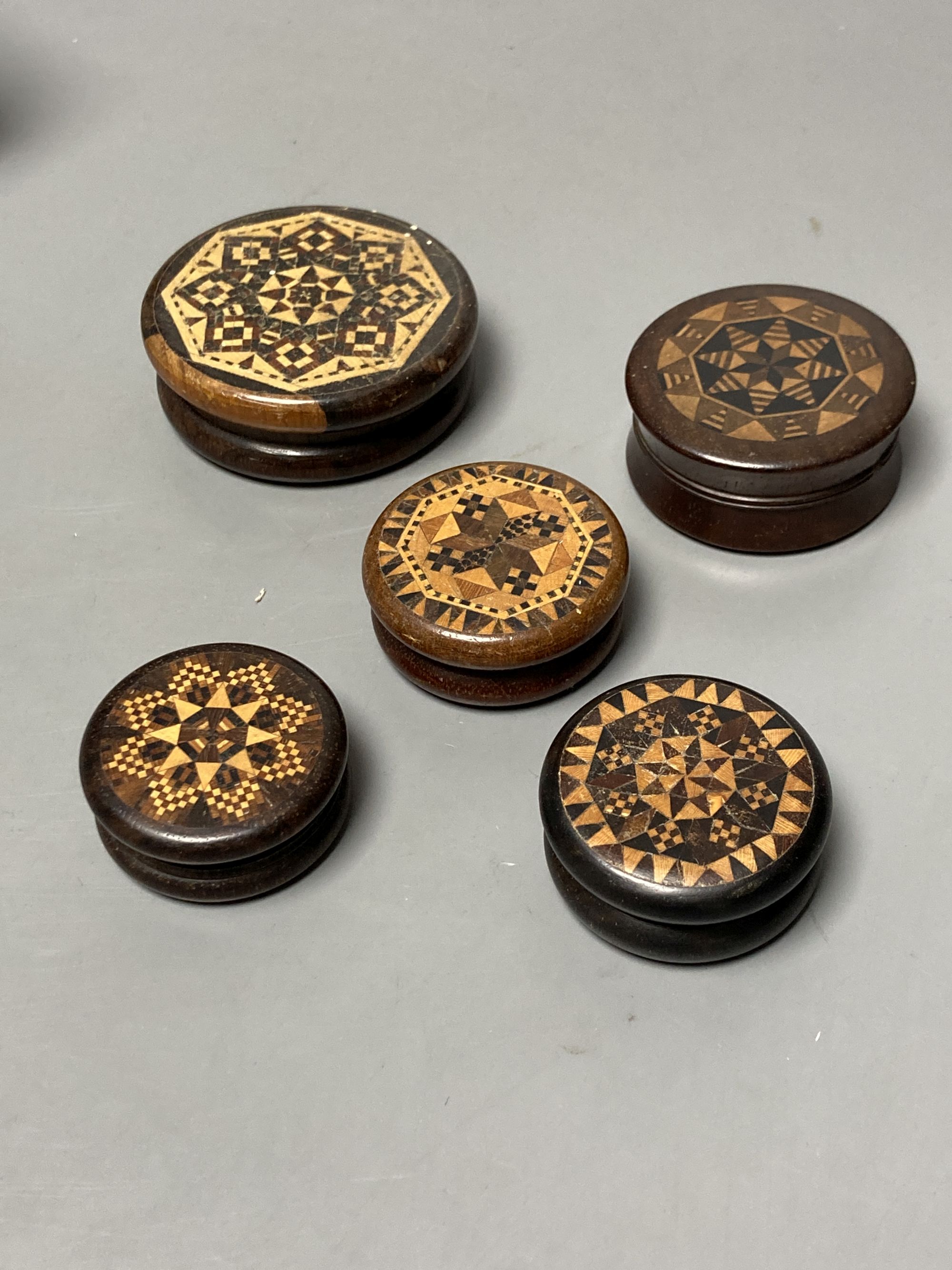 Five Tunbridge ware turned rosewood or mahogany boxes, late 19th/early 20th century, largest 5.8cm, the covers inlaid with tesserae or half square mosaic, one enclosing a compass, 3.8cm
